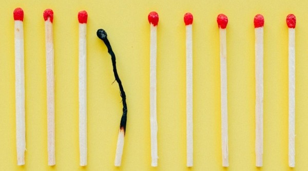 Row of matches on a yellow background with one burned match in the center.