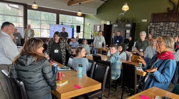 A group of people listen to an Elder speak during a workshop with the Shoalwater Bay Indian Tribe in Washington state.