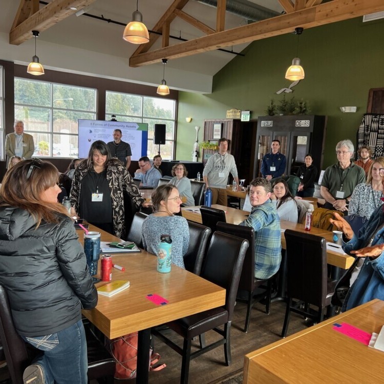 A group of people listen to an Elder speak during a workshop with the Shoalwater Bay Indian Tribe in Washington state.