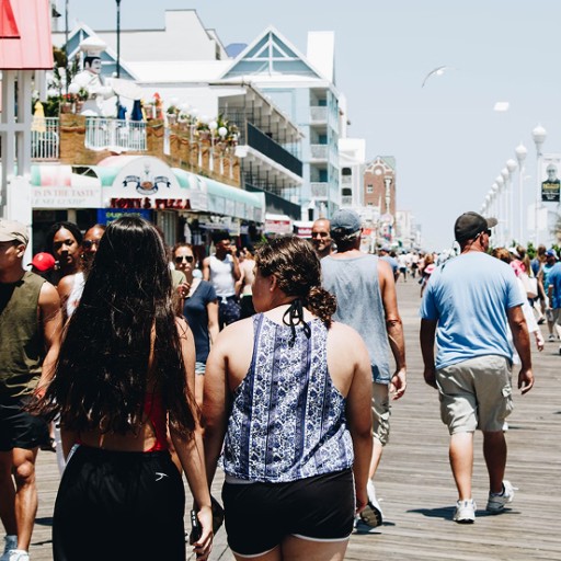 A boardwalk on a sunny day, busy with people checking out shops.