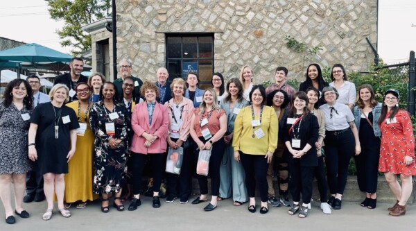 Large group of people pose for a photo in a courtyard.