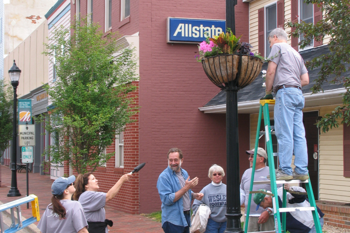 Photo showing a group of volunteers hanging planters in a downtown scene.