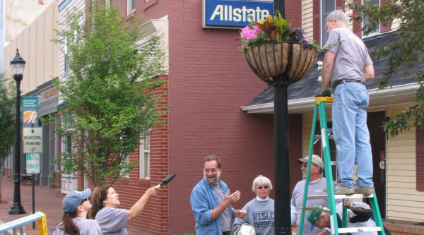 Photo showing a group of volunteers hanging planters in a downtown scene.