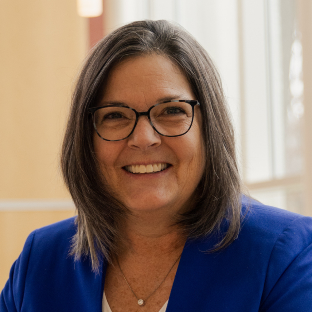 Woman with brown hair and glasses smiling