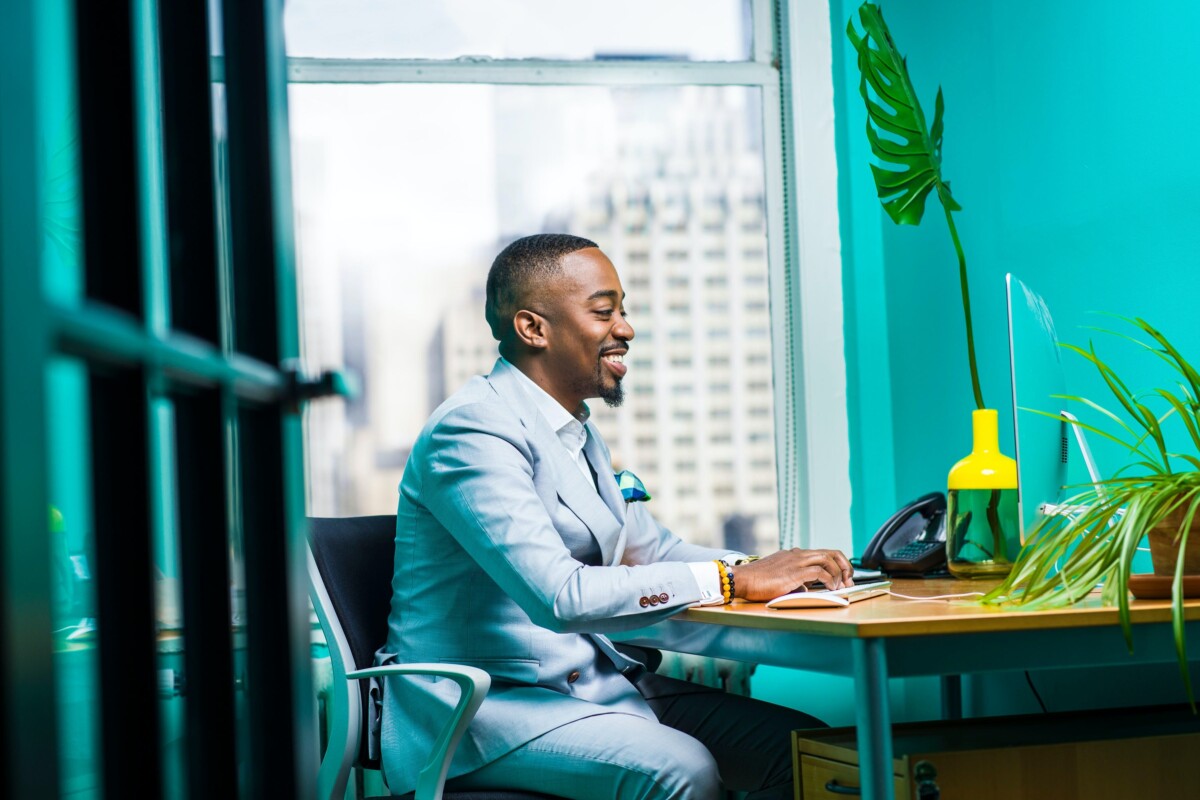 A man in a suit sits in an office working on a computer.