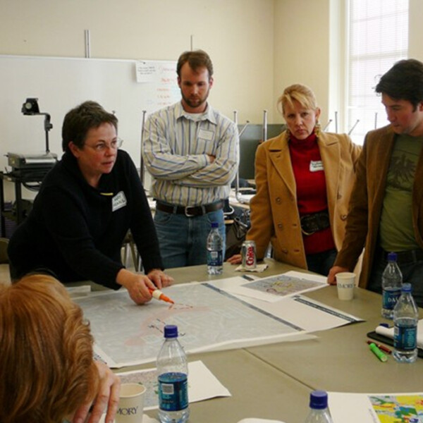 Mary Means, the "Mother of Main Street" with colleagues standing around a table mapping out a plan.