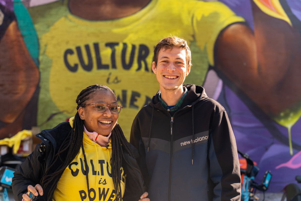 A woman and man standing in front of a mural that reads "Culture is Power" in Chicago, Illinois.