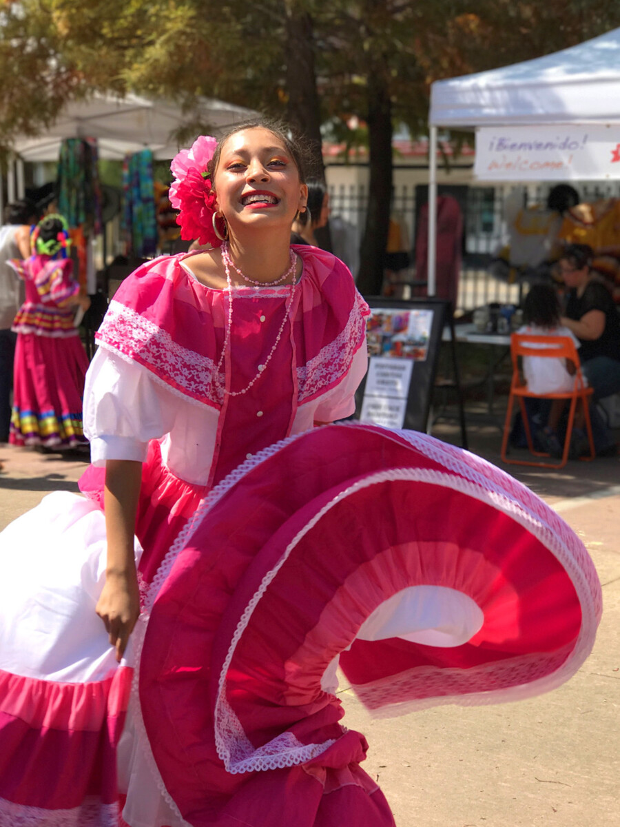 Ballet folklorico dancer swirls the skirt of her bright pink dress.