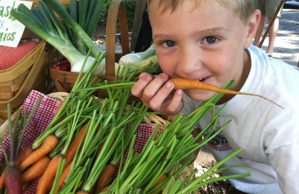 A child bites into a carrot.