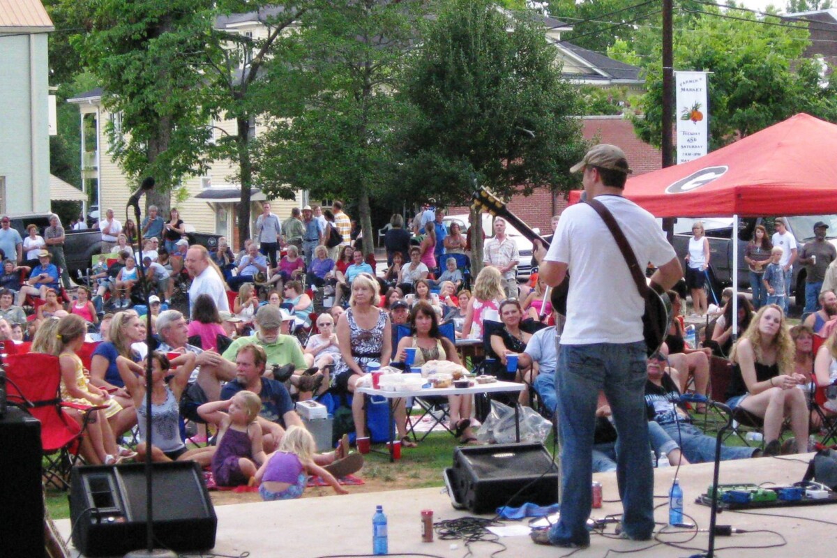 A guitarist performs to hundreds of people.