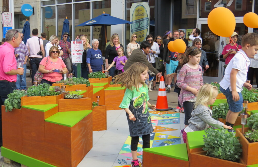 Children play on and explore a parklet while adults observe.