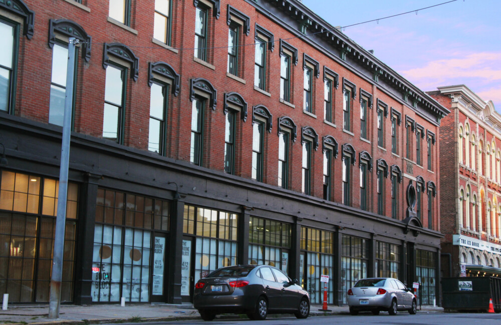 A large, three story brick building with floor to ceiling windows.