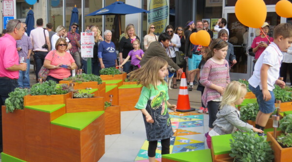 Children play on and explore a parklet while adults observe.