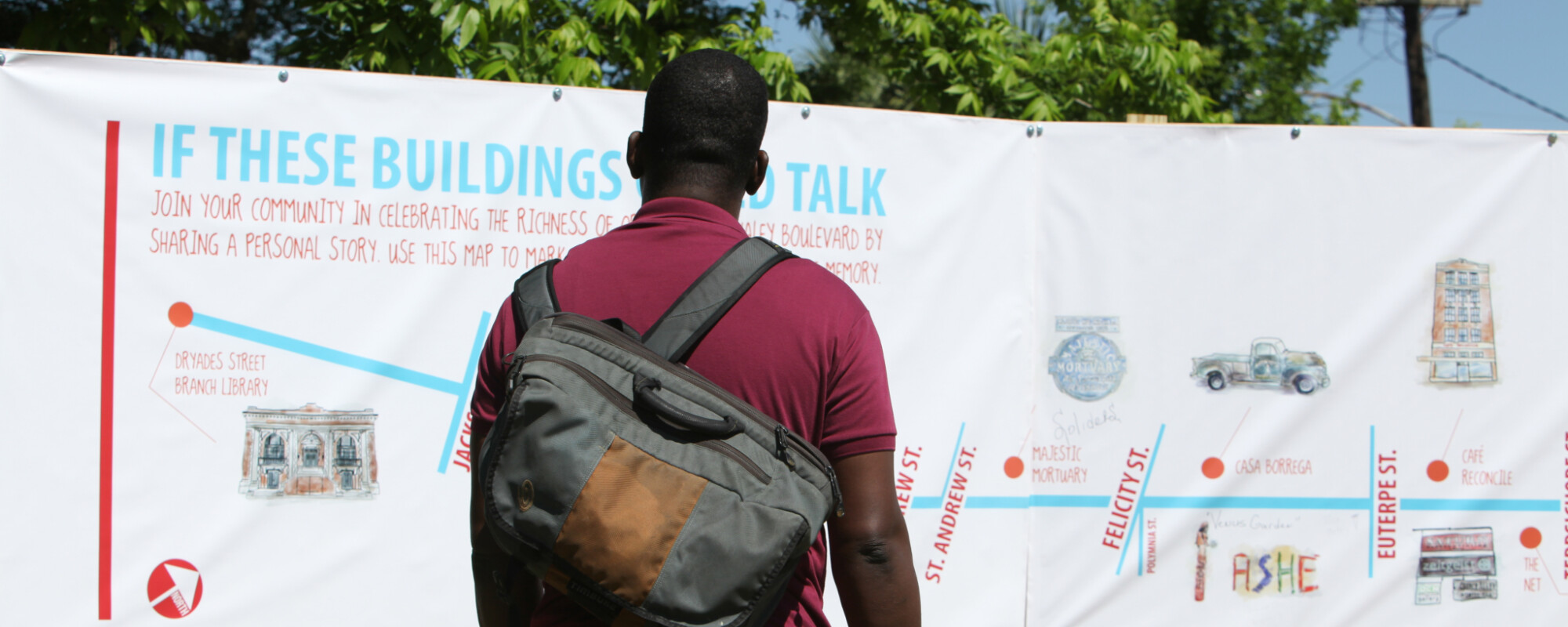 A man engages with a large outdoor installation outlining the history of buildings.