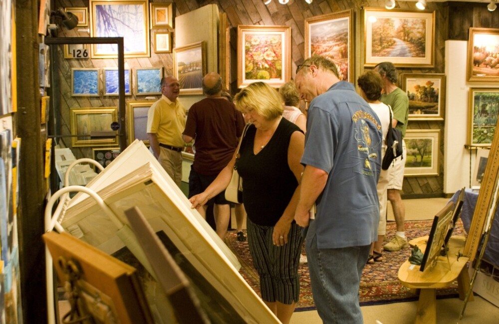 People peruse artworks in a gallery.