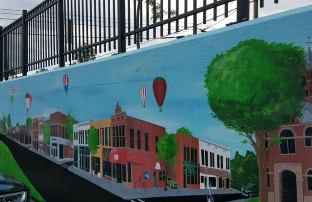 Mural depicting a downtown street with air balloons floating in the sky.