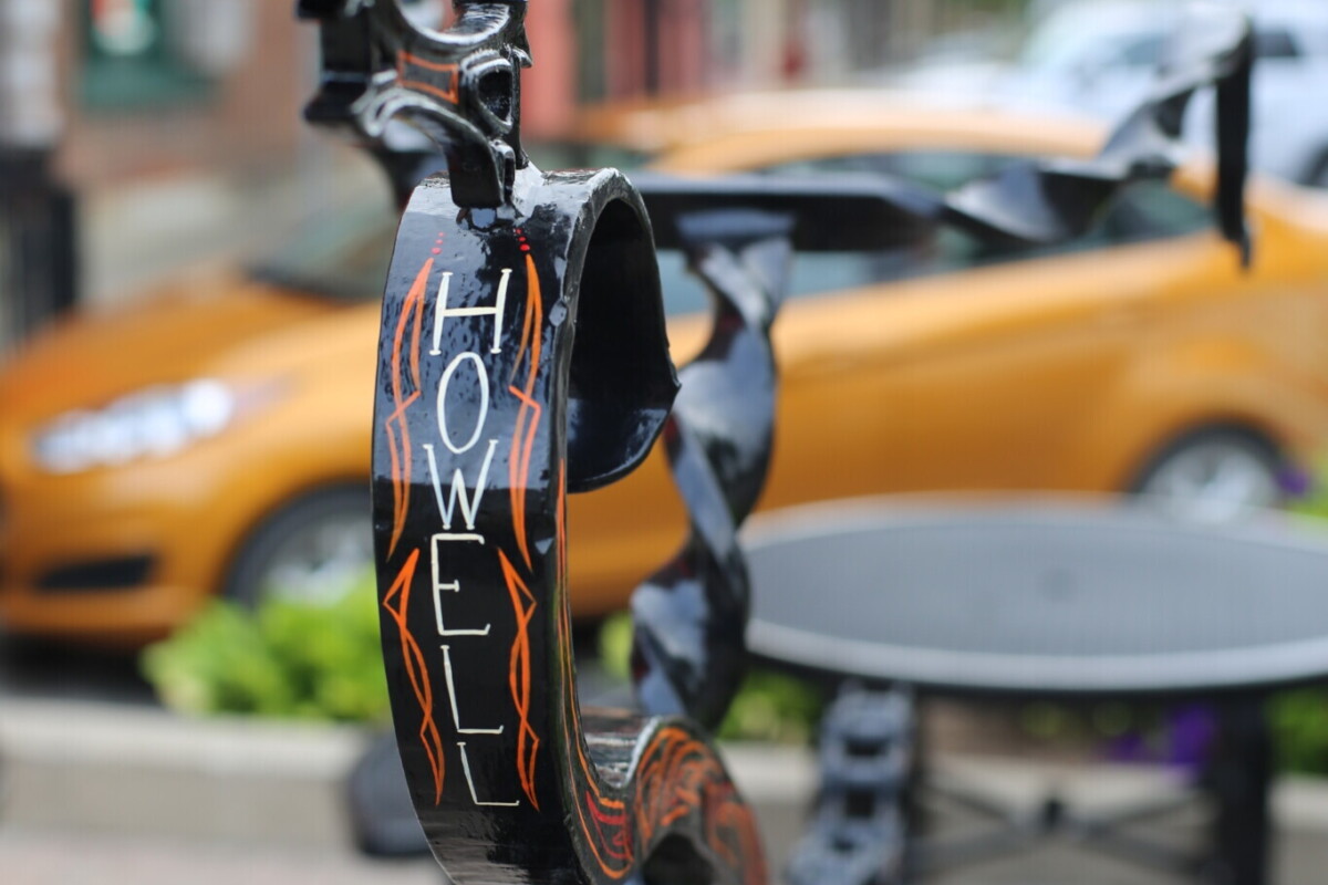 Shiny, black wrought iron bike rack with "Howell" painted in white.