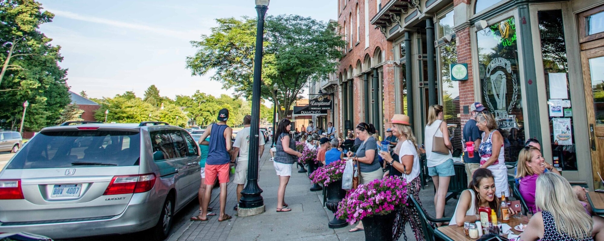 People sit at tables in a sidewalk patio area.