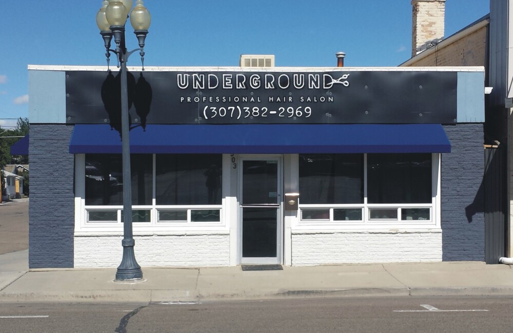 Single story retail storefront with bright blue awning.