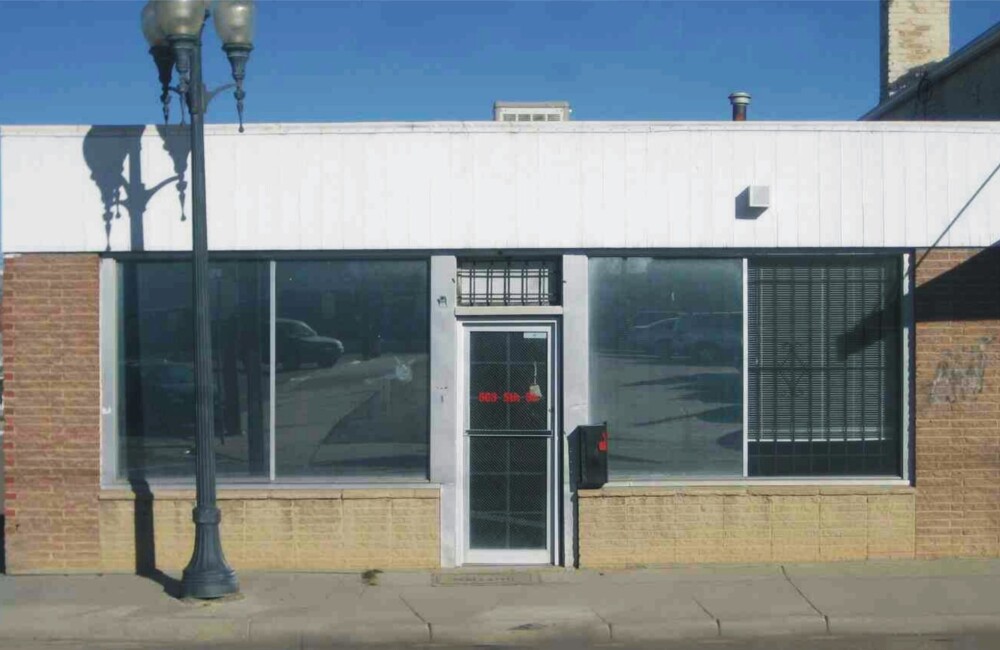 Vacant and weather worn single story retail storefront.