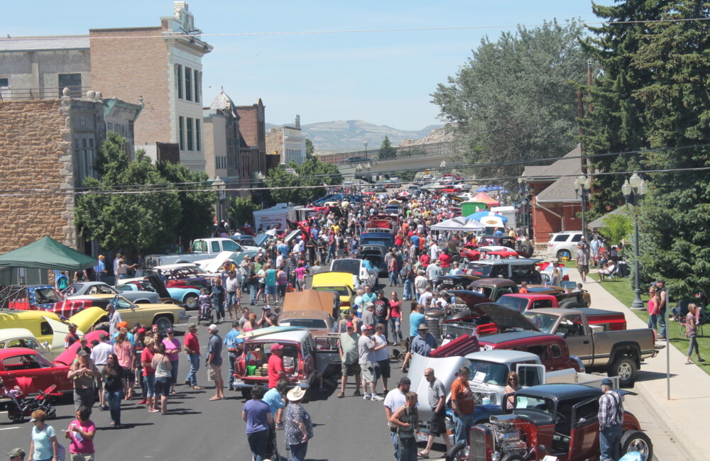 People stroll along a main street checking out vintage cars parked on both sides.