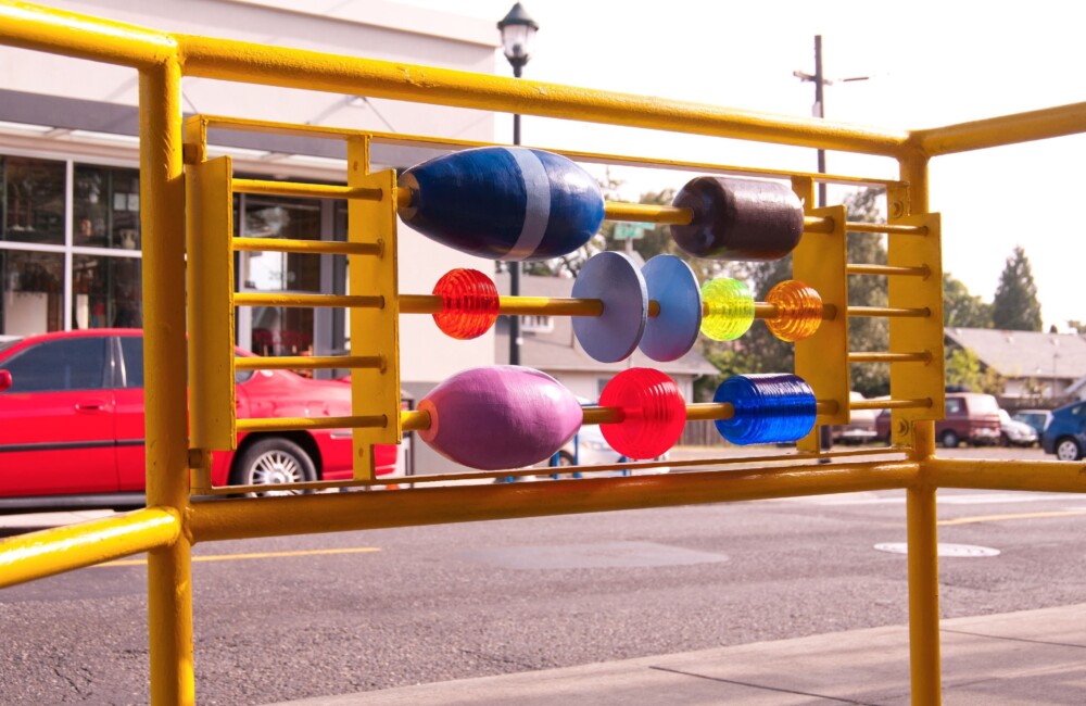 Sculptural elements of different sizes, shapes, and colors adorn a bus stop railing.