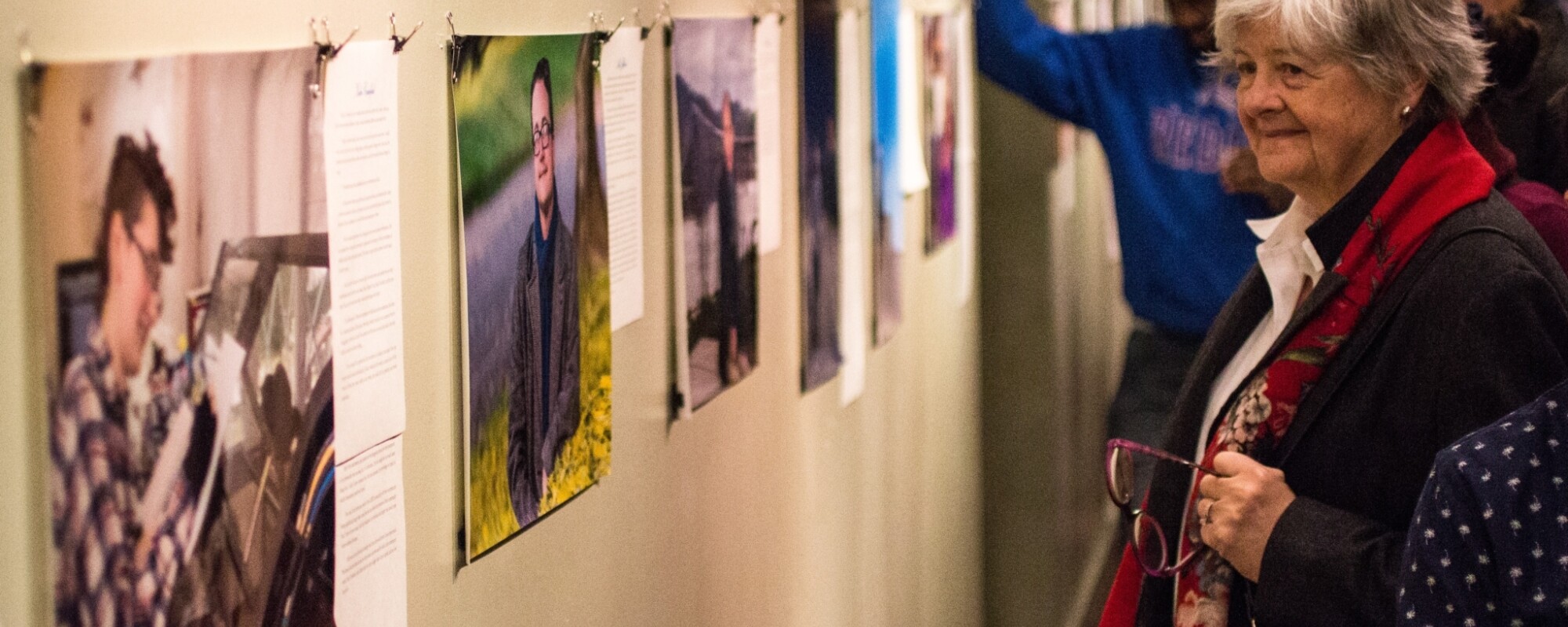 People look at photographs displayed in an art gallery.