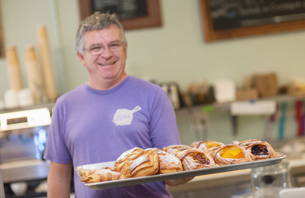 A man presents a tray loaded with pastries.
