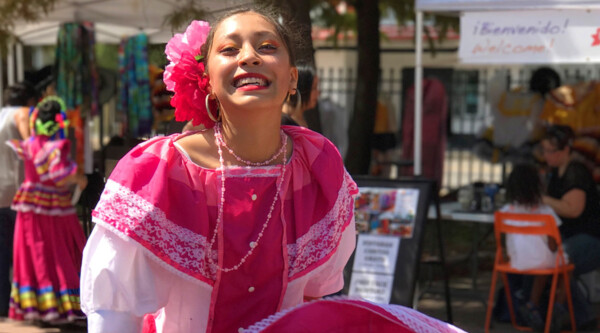 Ballet folklorico dancer swirls the skirt of her bright pink dress.