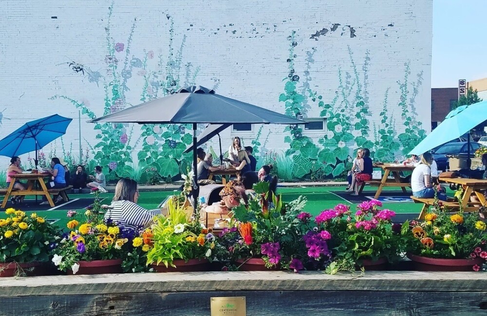 Parking lot turned into an outdoor seating area complete with bright flower planters and picnic tables.