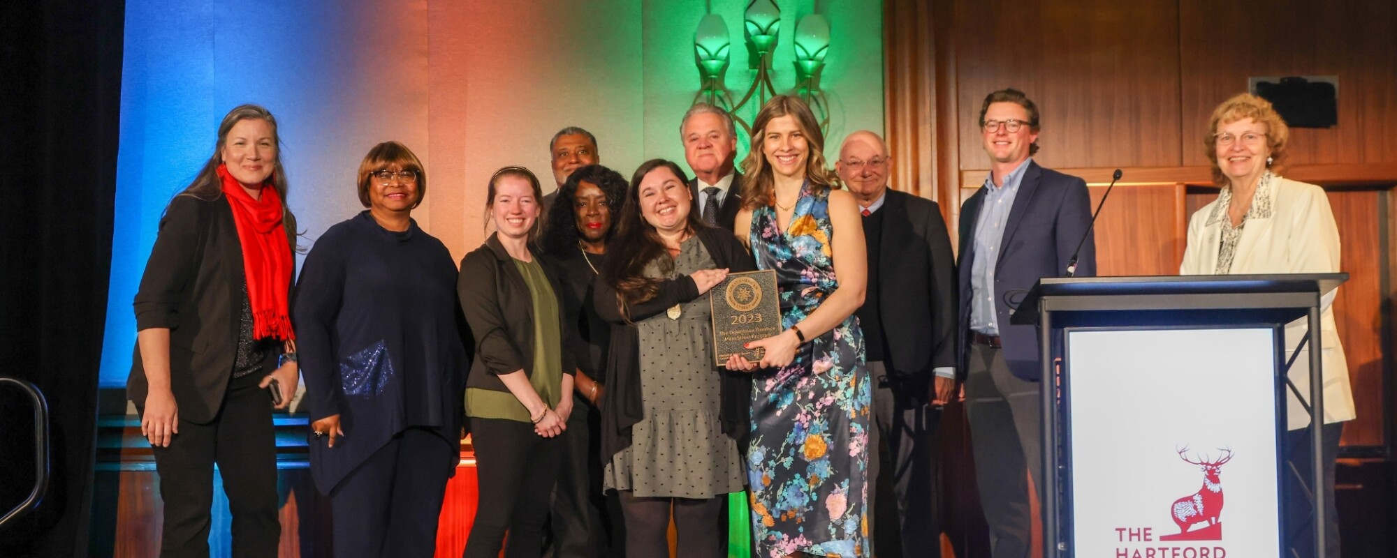 A diverse group of people pose and smile on stage during an award ceremony.