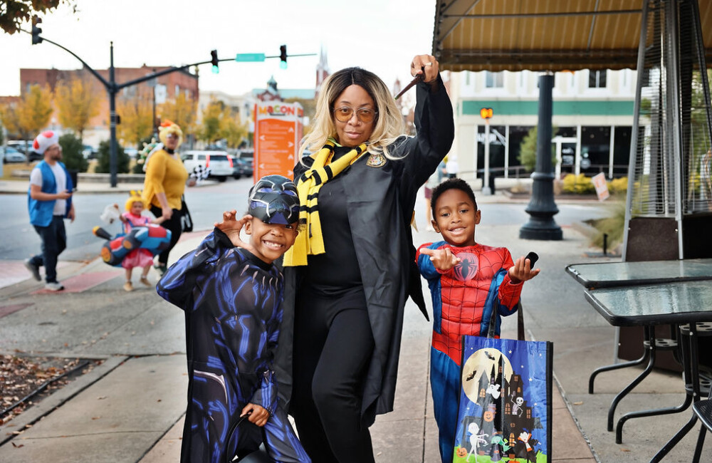 A woman and two children wearing costumes pose as their characters.