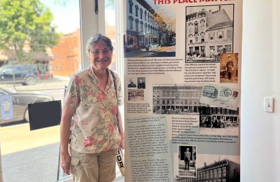 A woman smiles while standing next to a tall pop-up banner featuring information about a historic building.