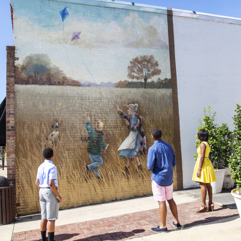 Three people gaze at a mural.