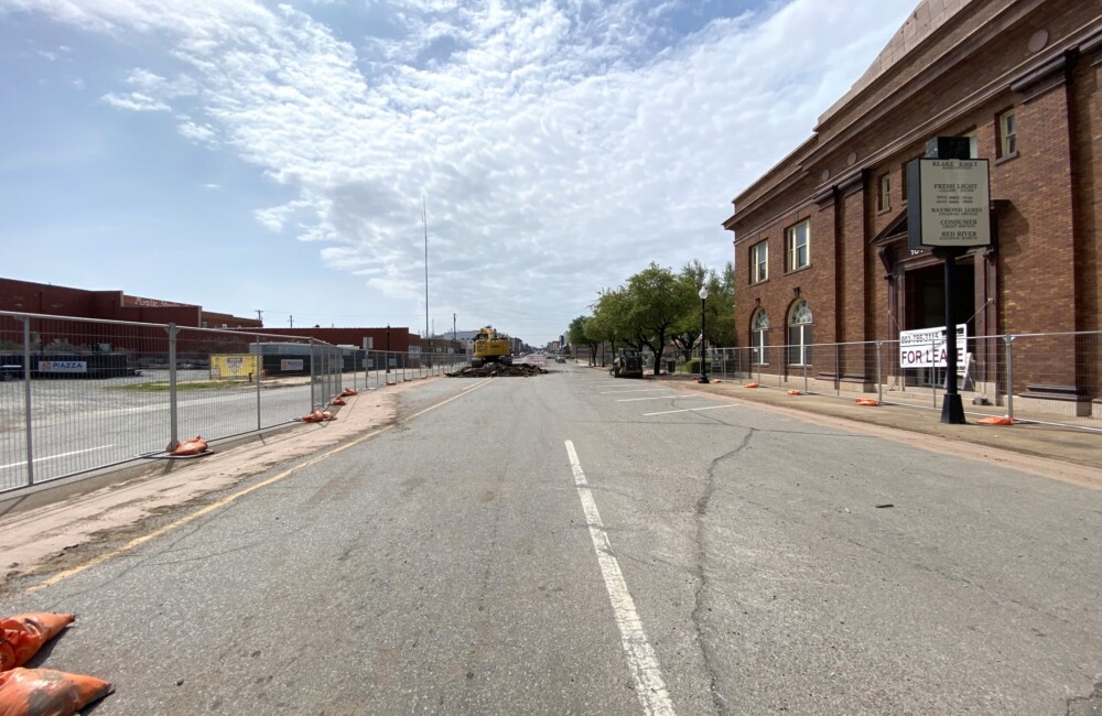 A wide, two-lane street with deteriorating sidewalks.