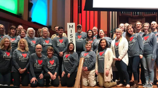 A large group of people wear matching shirts while posing for a group photo.