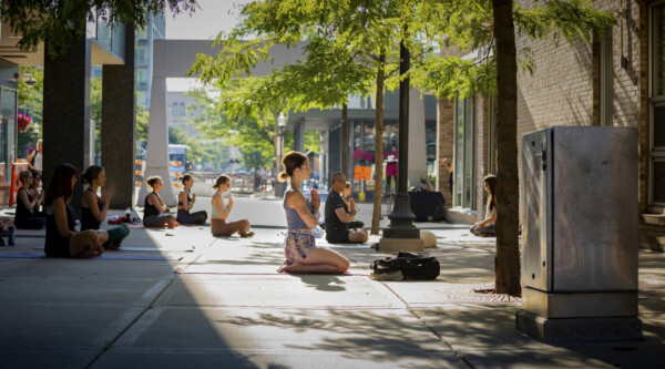 People practicing yoga in an outdoor plaza.