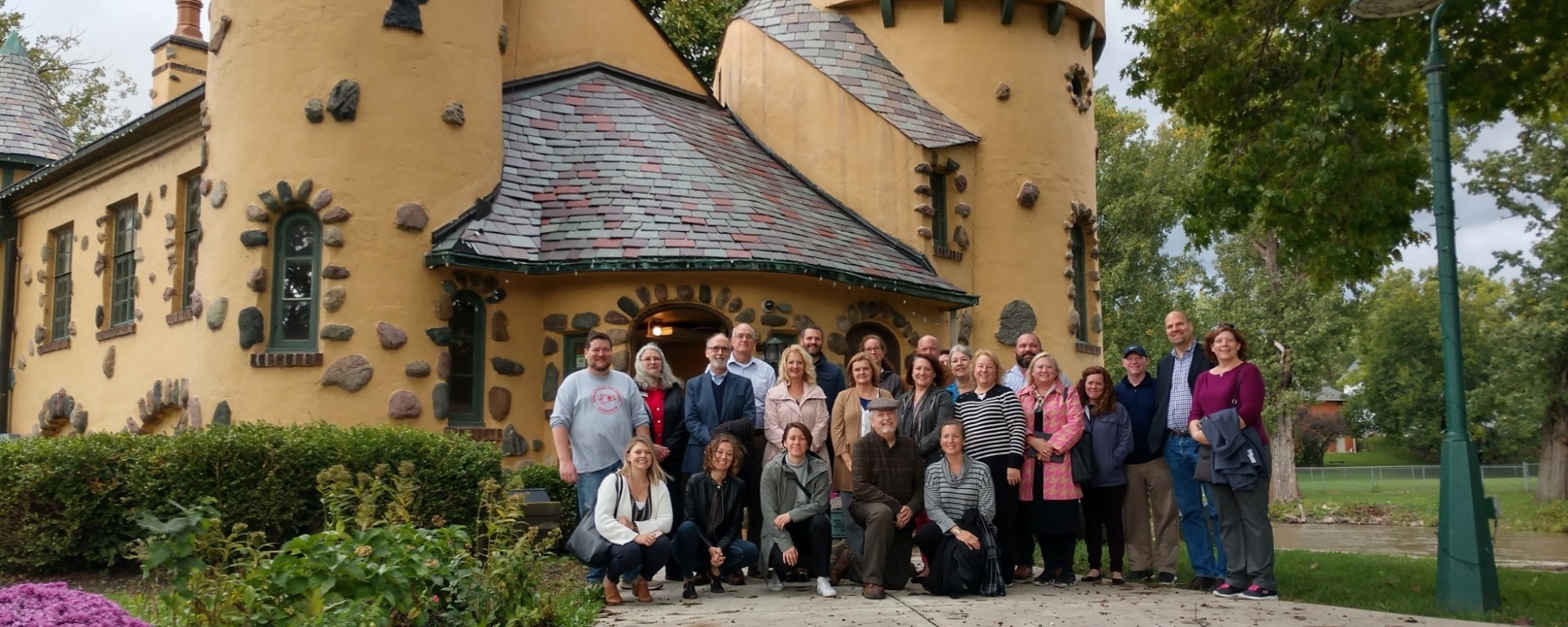 A large group of people gather for a group photo in front of the historic Curwood Castle.