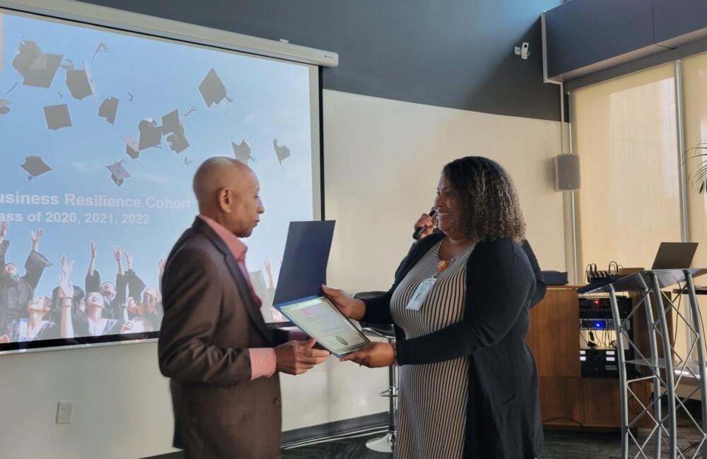 A woman (right) presents a man (left) with a certificate.