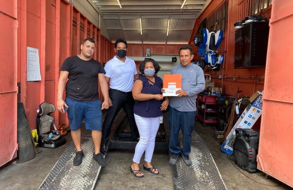 A small group of people stand inside an auto repair bay.