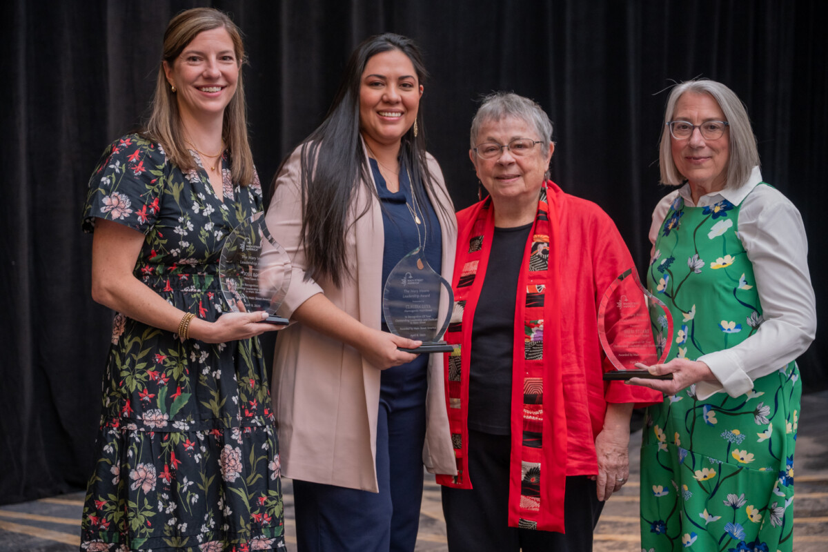 Cuatro mujeres posan para una foto de grupo, tres sostienen premios.