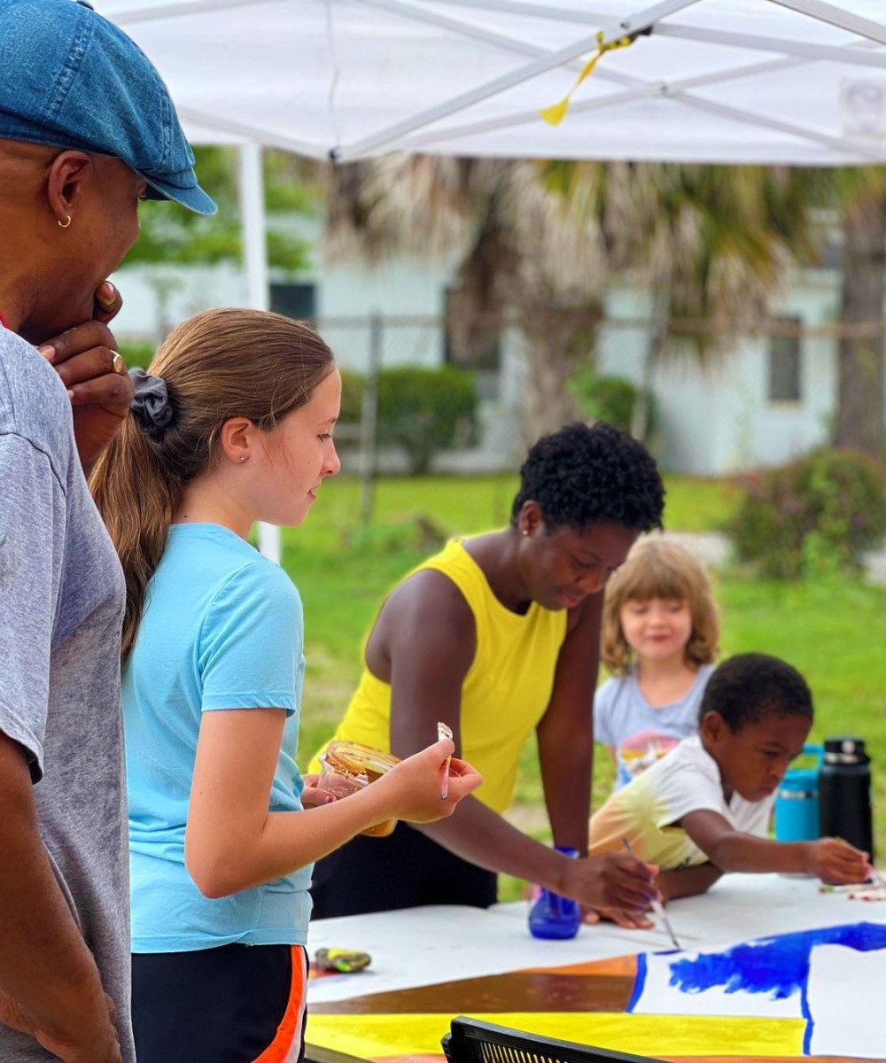 Adults and children create art at an outdoor event.