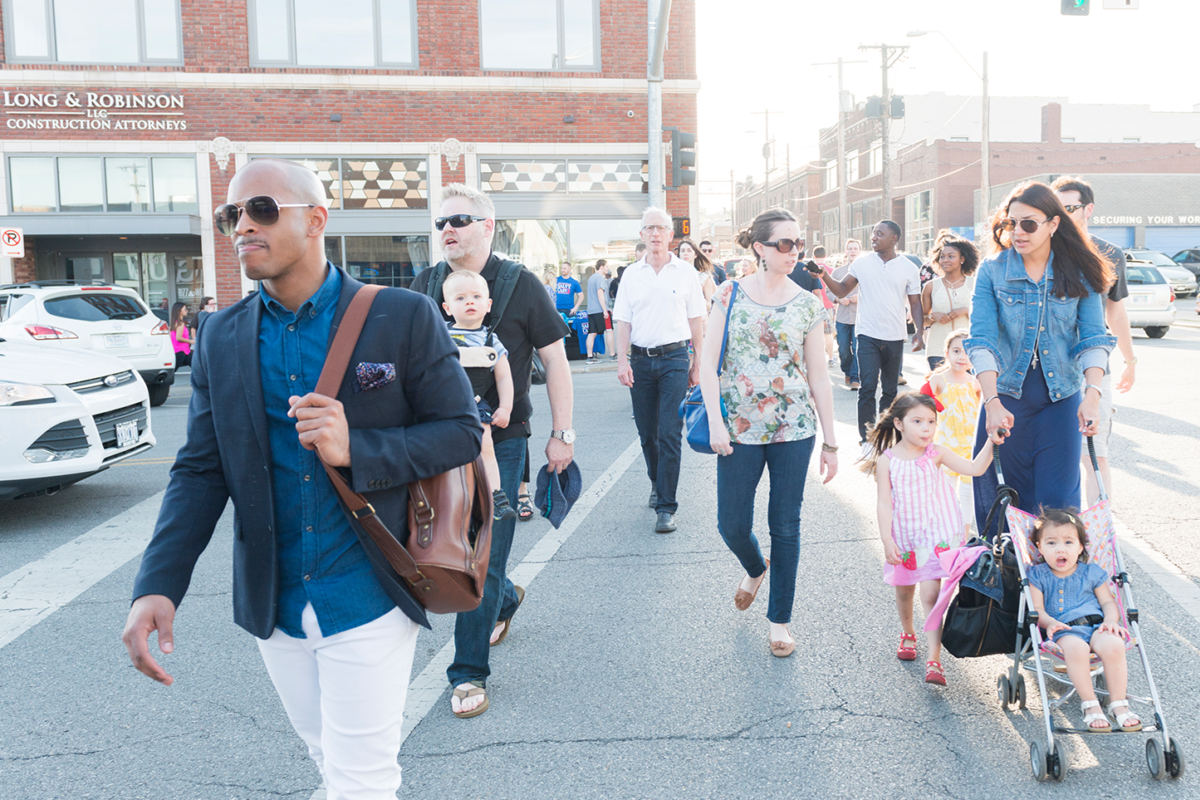 Group of people walking across a busy street.