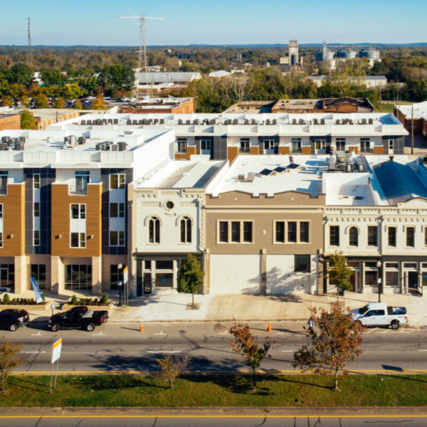 Aerial view of a street with commercial and upper story residential buildings.