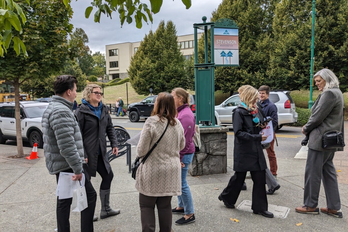 People gather in small groups on a sidewalk.