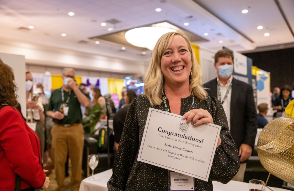 A woman smiles while holding up a certificate.