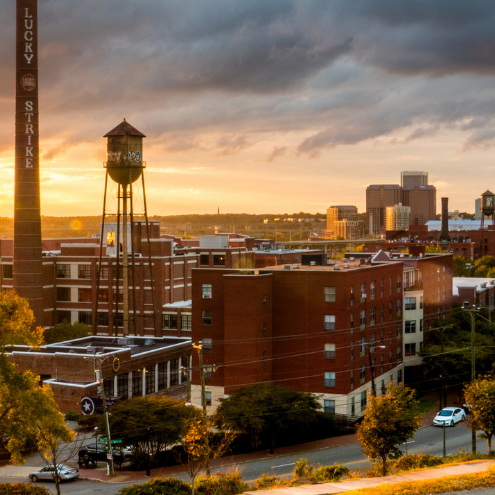 Sun setting behind a brick building-lined street.