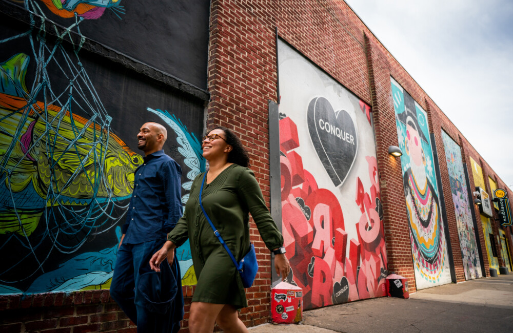 Two people walking by murals on Front Street in Fishtown.