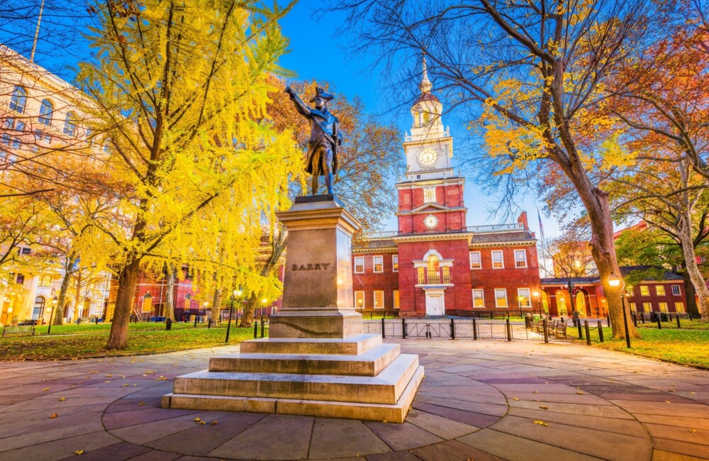 Bronze statue on a tall pedestal with Independence Hall in the background.