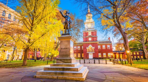 Bronze statue on a tall pedestal with Independence Hall in the background.